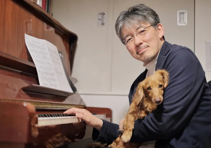 犬を抱いてピアノを弾く男性