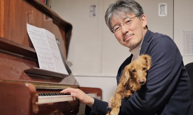 犬を抱いてピアノを弾く男性
