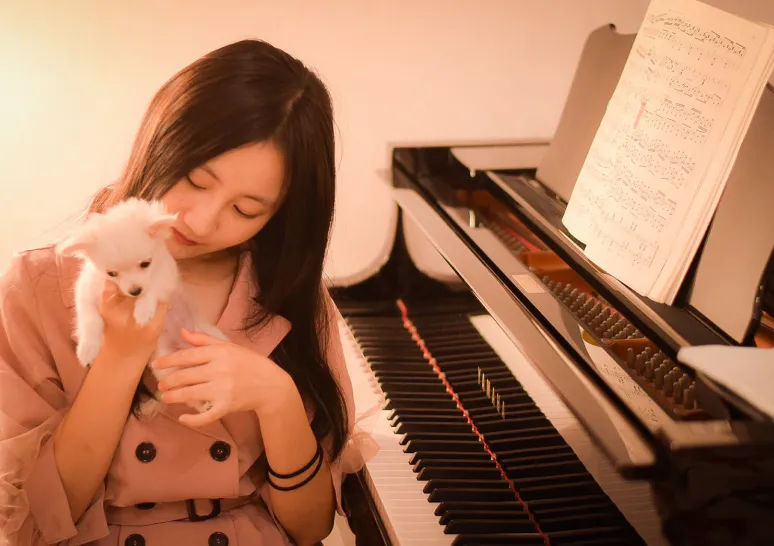 犬を抱っこしてピアノの前に座る女性